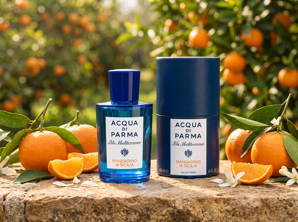 Acqua di Parma Blu Mediterraneo Mandarino di Sicilia Eau de Toilette 180ml bottle and blue cylindrical box on a sunlit stone ledge with fresh mandarin oranges